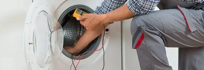 Dryer repair technician inspecting and repairing a clothes dryer in Lowell, MA