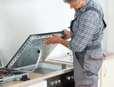 Appliance repair technician installing a built-in cooktop in Lowell, MA