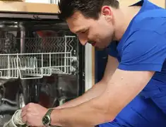 Dishwasher repair technician inspecting and servicing an open dishwasher in Lowell, MA
