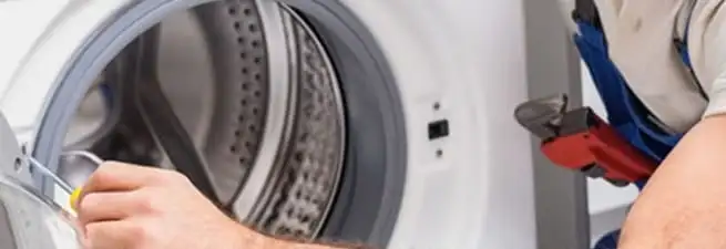 Appliance technician repairing a clothes dryer drum and internal parts in Lowell, MA