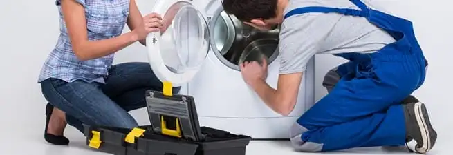 Washer repair technician inspecting a front-load washing machine with tools in Lowell, MA