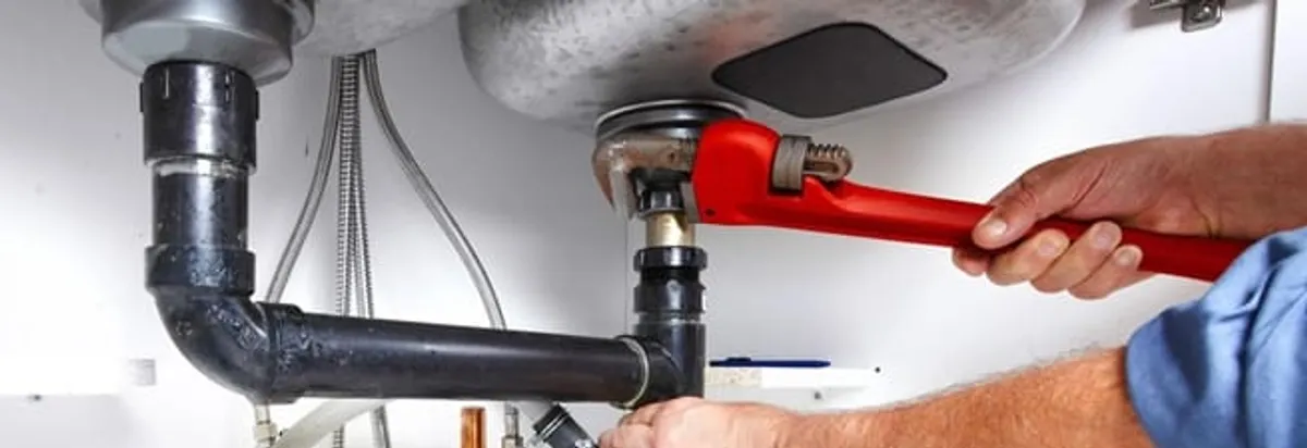 Garbage disposal repair technician tightening the sink drain and disposal connection in Lowell, MA
