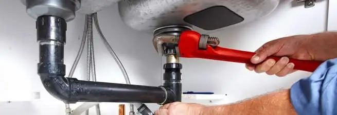 Garbage disposal repair technician tightening the sink drain and disposal connection in Lowell, MA
