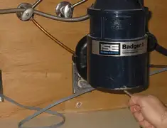 Garbage disposal repair technician tightening the mounting ring under a sink in Lowell, MA