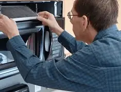 Appliance repair technician replacing a microwave vent filter in Lowell, MA