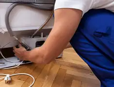 Appliance repair technician fixing refrigerator water line and connections in Lowell, MA