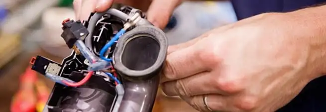 Vacuum repair technician reconnecting wiring and components in Lowell, MA