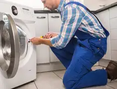 Washing machine repair technician servicing a front-load washer in Lowell, MA