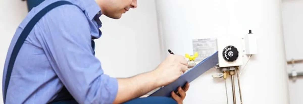 Water heater repair technician inspecting the unit and recording service notes in Lowell, MA