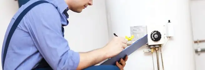 Water heater repair technician inspecting the unit and recording service notes in Lowell, MA