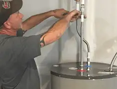 Water heater repair technician tightening supply line connections in Lowell, MA