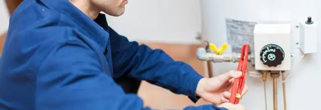 Water heater repair technician adjusting the temperature control and gas valve in Lowell, MA